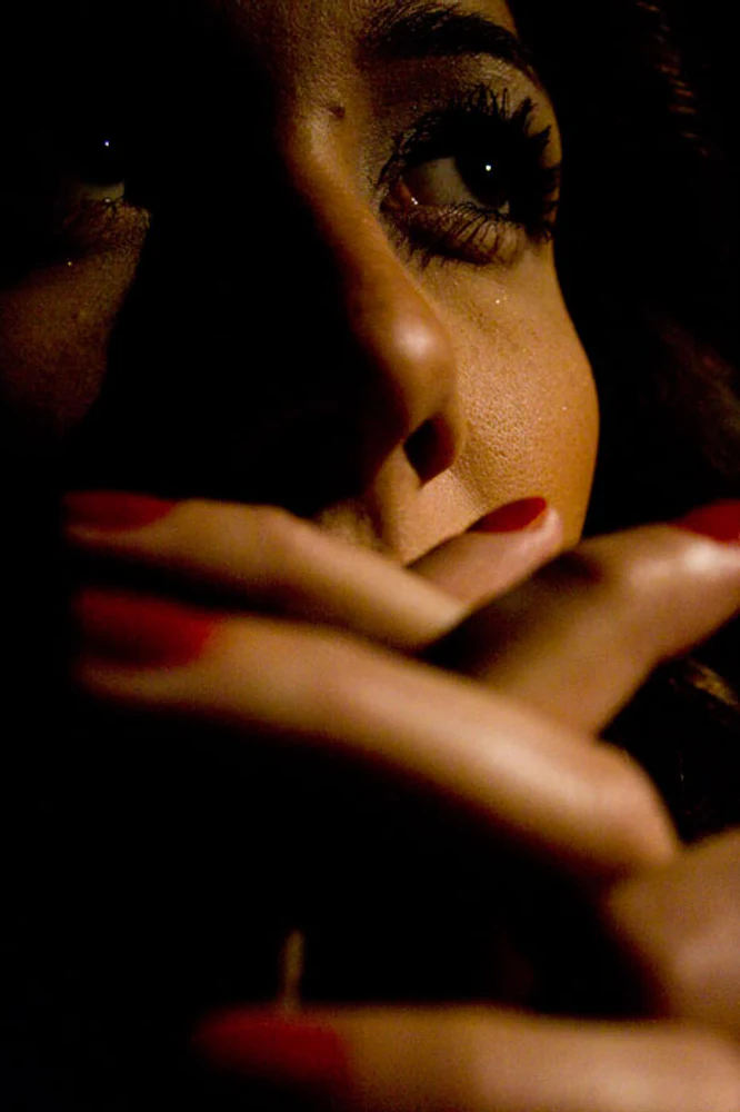 Retrato fechado de Karla Jacobina com destaque para olhos, mãos, unhas vermelhas, luz lateral e sombras intensas. Fotografia autoral de Eduardo Sardinha — Sardinha17. Palavras-chave: close, olhar, mãos, maquiagem, vermelho, retrato feminino, luz dramática.