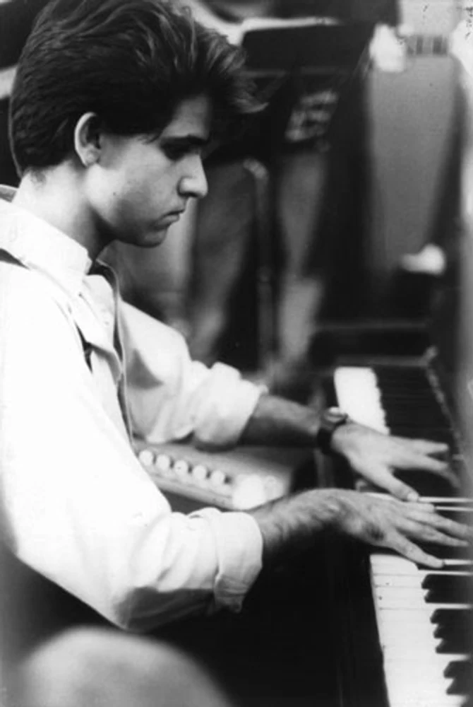 Rogério Mello toca piano em fotografia vertical preto e branco da Mississampa Blues Band. Elementos visíveis: pianista, piano acústico, teclas, mãos, perfil, instrumento musical, concentração, luz e sombra. Fotografia e arquivo autoral de Eduardo Sardinha / Sardinha17.